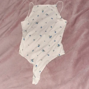 Body strl M - En vit string-body med blåa blomor på närmare bestämt blåklint i strl M från H&M kom aldrig till användning