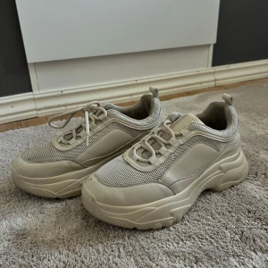 Chunky beige/ krämvit, 39, dam - Chunky sneakers i beige med grov sula. Skorna har snörning och en blandning av syntet och textilmaterial som ger en sportig vibe. Perfekta för dig som gillar streetstyle och vill ha en trendig look. Varan har lite defekter, dom ska tvättas och putsas 