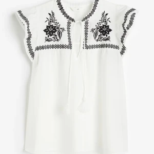 Vit blus med broderi från H&M - Supersöt vit blus från H&M med svarta broderade blommor🤍