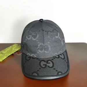 Svart keps från Gucci med GG-mönster - Snygg svart keps från Gucci med ikoniskt GG-mönster över hela kepsen. Kepsen har böjd skärm med svart kant och justerbart spänne bak i skinn. Tillverkad i slitstark polyester och har en exklusiv känsla som lyfter din stil.