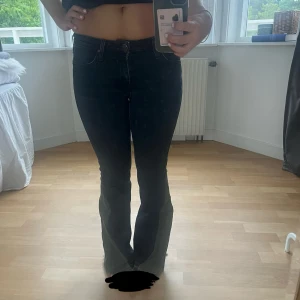 Svarta bootcut jeans från lee - Säljer ett par svarta bootcut jeans med rå, fransig kant nertill. Jeansen har klassisk femficksdesign, smal passform upptill och utsvängda ben. Snygg lowwaist-modell i stretchigt denim som sitter riktigt bra och ger en schysst siluett.