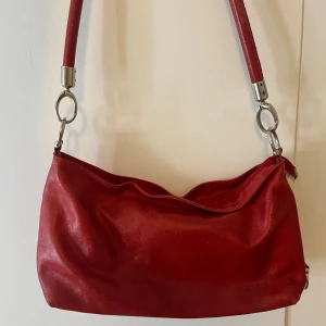 Röd axelväska  - Snygg röd väska köpt på vinted. Den har lite defekter på undersidan och på sidan som man ser på bild 4 och 5. Skriv för fler bilder eller om ni har frågor 💗