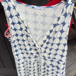 Flash omlottkllnning  blåvit prickig stl M - Flash ärmlös omlottklänning i blått och vitt med stort prickigt mönster. Omlottmodell med v-ringning och mjukt, lätt material som känns skönt mot huden. Perfekt för varma dagar när du vill ha något luftigt och snyggt.