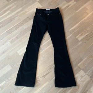Svarta bootcut jeans från Gina - Snygga svarta jeans med bootcut-modell och klassisk femficksdesign. Byxorna har normal midja och raka ben som blir vidare nedtill. Perfekta för dig som gillar en retrovibe och vill ha ett par stilrena svarta jeans i garderoben.