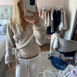 Beige omlottstickad tröja - Supermysig beige stickad tröja med omlottmodell och knyt i sidan. 