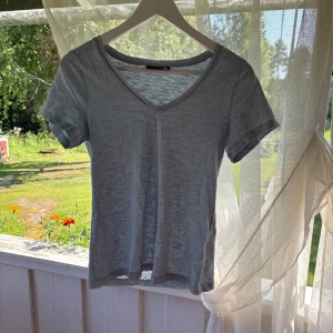 Ljusblå v-ringad t-shirt KappAhl XS - Enkel och stilren ljusblå t-shirt från KappAhl i storlek XS. T-shirten har v-ringning, korta ärmar och är tillverkad i ett tunt, mjukt bomullstyg. Perfekt för en chill och avslappnad look.