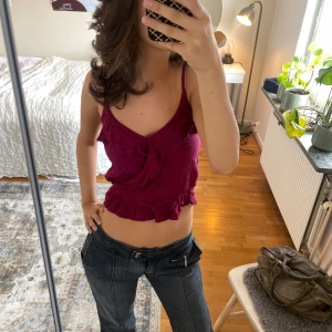  linnetopp från Hollister - Supersöt lila/vinröd linnetopp från Hollister med smala axelband, v-ringning och volangdetaljer både framtill och längs nederkanten. Köpt på Sellpy men aldrig använd Perfekt för dig som gillar en feminin och trendig look. Toppens material känns mjukt och lätt mot huden.