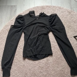 Svart långärmad blus med puffärm - Snygg svart blus med långa puffärmar och markerad axel. 