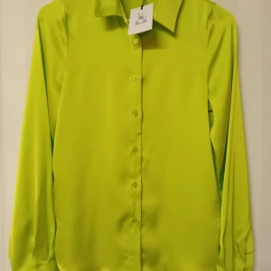 Neongul skjorta med Bik Bok märke, XS - Snygg neongul skjorta från Bik Bok i 100% polyester. Skjortan har klassisk krage, knäppning framtill och långa ärmar med manschett. Perfekt för dig som vill sticka ut med en färgstark look. Kan skickas med extra pris via post.