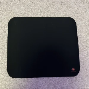 Svart mus matta  - Bilderna visar en svart musmatta från Deltaco Gaming, inte en bok. Ingen information om boktitel, författare eller innehåll kan identifieras från bilderna.