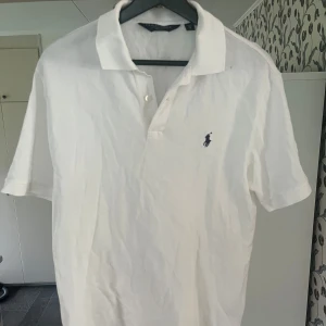 Vit pikétröja från Polo Ralph Lauren - Vit Ralph lauren pike i storlek S men Sitter som L/XL. Köpt på sellpy. Skick 8,5/10 använd men inga defekter. Skriv vid frågor eller liknande!