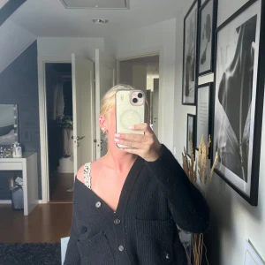 Svart kofta från Polo Ralph Lauren - Svart ribbstickad kofta från Polo Ralph Lauren med v-ringning, stora knappar och två fickor framtill. Modellen är lite croppad och har lång ärm. Perfekt för lager-på-lager och chill vibe - den passar perfekt om man är frusen en sommarkväll!☀️👗