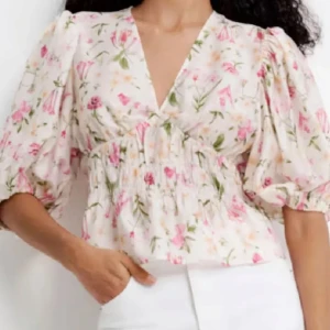 Blommig blus med puffärm och v-ringning - Supersöt blommig blys från H&M.                             Slutsåld.                           Blusen har v-ringning, smockad midja och puffiga trekvartsärmar.              Endast testad!
