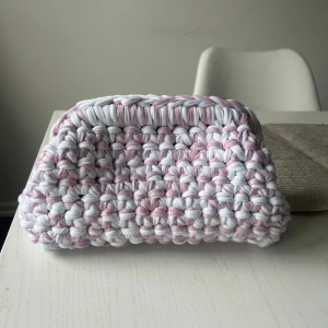 Handvirkad rosa och vit kuvertväska - Superfin handvirkad kuvertväska i rosa och vitt med chunky känsla. Väskan är rektangulär och har ett öppet fack,.