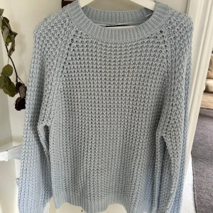Ljusgrå stickad tröja med grov struktur - Supermysig ljusgrå stickad tröja med grov struktur och rund halsringning. Perfekt för kyliga dagar och enkel att matcha med jeans eller kjol. Långärmad och med breda ribbade muddar vid ärmslut och nederkant.