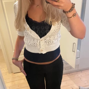 Vit stickad kofta - Supersöt vit stickad kofta med kort ärm och snyggt hålmönster. Croppad modell med bred ribbad kant nedtill och två stora knappar framtill💘💘