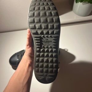 Valentino Garavani VLTN sneakers svart/vit - Svarta sneakers från Valentino Garavani med stor vit VLTN-logga på sidan och vit detalj på hälen. Klassisk rund tå, snörning och platt sula med mönstrad undersida. Tillverkade i skinn för en lyxig känsla och stilren look. Inget ingår därefter priset!