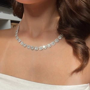 Glittrigt silverhalsband med stenar - Säljer ett snyggt halsband i silverfärg med glittrande stenar som sitter tätt i ett blommigt mönster. Endast använd en gång😊