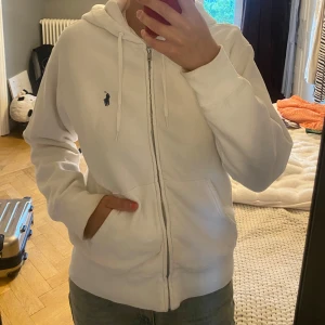 Ralph louren hoodie  - En vit zip up hoodie från Ralp Louren! Köpt för några årsedan men väldigt bra skick ändå. Lite slitningar på armuddarna, alltså lite mörkare färg.