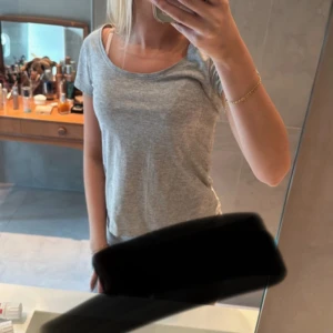 Grå basic t-shirt med rund hals - Enkel och stilren grå t-shirt med rund halsringning och korta ärmar. Perfekt för en clean och avslappnad look. T-shirten har en normal passform och är gjord i mjuk bomull som känns skön mot huden.