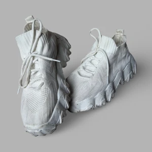 Chunky vita sneakers strl 39 - Chunky vita sneakers med stickad ovandel och högt skaft i strumpmodell. Snyggt mönstrad mesh och ribbad kant upptill. Griv sula med svarta prickar ger en cool vibe. Skorna har snörning och är tillverkade i syntetmaterial. Perfekt för dig som gillar streetstyle och vill sticka ut.