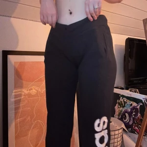 Svarta Adidas mjukisbyxor med logga - Svarta mjukisbyxor från Adidas med stor vit logga längs ena benet och mindre logga vid fickan. Storlek M men skulle säga att de passar som XS/S