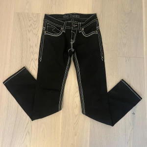 Svarta jeans med kontrastsömmar BM Denim - Svarta jeans från BM Denim med tydliga vita kontrastsömmar och snygga detaljer på bakfickorna. Klassisk femficksmodell med raka ben och normal passform. Perfekta för dig som gillar en stilren look med lite edge.
