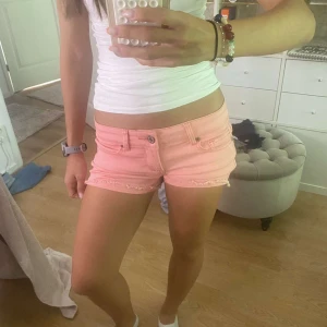 Ljusrosa jeansshorts från RE: - Säljer ett par korall jeansshorts från RE: i storlek XS. Modellen är lågmidjad med klassisk femficksdesign och råa, fransiga kanter nedtill. Shortsen har knapp och dragkedja framtill samt bälteshällor. Perfekta för varma sommardagar! Skriv om du undrar över något!! 🥰