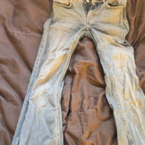  ljusblå bootcut jeans - Säljer ett par klassiska jeans i ljusblå denim. De har bootcut passform, fem fickor och dragkedja med knapp. Perfekta för dig som gillar retrovibbar och vill ha ett par jeans med snyggt fall över skorna.