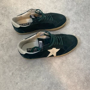 Golden goose sneakers - Säljer ett par gröna mocka golden goose ball star sneakers. Skorna är i bra skicka inga defekter osv bara smutsiga (Skicka 7,5/10). Storlek 42 box ingår, skriv vid minsta fundering eller vid behov av fler bilder. Kan gå ner i pris vid snabb affär.