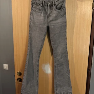 Grå bootcut jeans från Denim Day - Snygga grå jeans från Denim Day i bootcut-modell. Jeansen har klassisk femficksdesign, bälteshällor och dragkedja med knapp. Materialet är jeans och färgen är en schysst mellangrå ton som passar till det mesta.