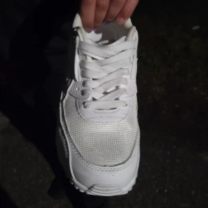 Vita Nike Air Max sneakers - Fräscha helvita Nike Air Max sneakers med klassisk siluett. Skorna har mesh och skinnpaneler, synlig Air Max-dämpning i sulan och snörning framtill. Perfekta för dig som gillar en clean och sportig look.