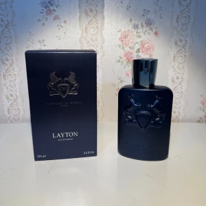 Parfums de Marly Layton 125ml - Lyxig parfym från Parfums de Marly, Layton Eau de Parfum i en mörkblå, matt flaska med silverdetaljer och reliefmönster av två hästar. Flaskan rymmer 125 ml och kommer i en matchande elegant ask. Doften är känd för sin exklusiva och moderna känsla.