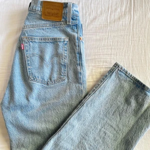 Levi's ljusblå ribcage full length jeans straight fit - Superfina Levi's jeans i ljusblå tvätt med raka ben och hög midja. Endast använda en gång då de tyvärr var för stora. Jeansen har knappgylf och är tillverkade i 99% bomull och 1% elastan för en skön passform. Perfekta för en avslappnad och tidlös stil💗Stl: 28/32 (slutsålda på hemsidan) Nypris: 1349:-
