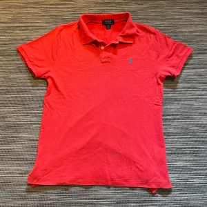 Röd pikétröja från Polo Ralph Lauren - Säljer en snygg piké från Ralph Lauren! Pikén är i mycket bra skick förutom två väldigt små hål längst ner på tröjan som man knappt ser när man använder den😊 Storleken är XL men passar mig som är S/M. Skriv till mig om ni vill ha måtten. Om ni har några andra frågor eller önskar flera bilder så är det bara att höra av er!