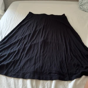 Svart långkjol från Even&Odd - Enkel och snygg svart långkjol från Even&Odd. Kjolen har en klassisk A-linjeform och är gjord i ett mjukt och lätt material som känns skönt mot huden. Perfekt för dig som gillar stilren och minimalistisk look.