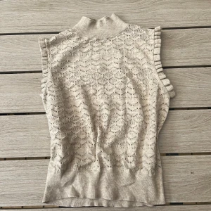 Beige stickad ärmlös topp Bik Bok - Supersöt beige stickad topp från Bik Bok med krage och volangdetaljer vid ärmöppningarna, använd fåtal gånger!