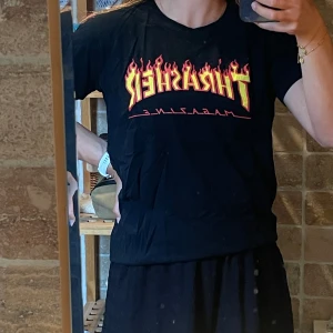 Svart Thrasher t-shirt med flames - Svart t-shirt från Thrasher med ikoniskt flames-tryck i gult och rött över bröstet. 