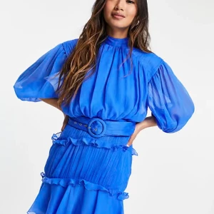 Blå volangklänning från ASOS Design - Supersnygg blå kortklänning från ASOS Design med volanger, puffärmar och bredt bälte i midjan. Klänningen har plisserad kjol, öppen rygg och är gjord i ett lätt, flowy material som känns lyxigt. Perfekt för dig som vill sticka ut!
