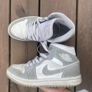 Nike Air Jordan 1 Mid grå/vit - Säljer ett par feta jordans!⭐️ Stiliga, sköna men passar inte längre. Ingen låda medföljer och lite smutsiga därav det låga priset. Original pris - 2200. Äkta skor👍