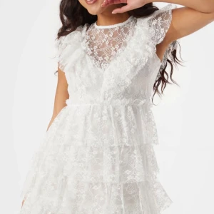 Studentklänning bubbleroom  - Superfin vit kortklänning i spets med volangdetaljer. Använd 1 gång och har inga fläckar eller defekter. Storlek XS