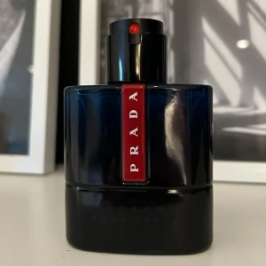 Prada Luna Rossa Ocean parfym - Snygg parfymflaska från Prada, Luna Rossa Ocean EDT. Flaskan är djupblå med svart och har en röd vertikal detalj med PRADA-loggan. Modern och stilren design, perfekt att ha framme på hyllan. Glasflaska med svart plastkork och röd sprayknapp. Ca 20/50ml kvar, box saknas
