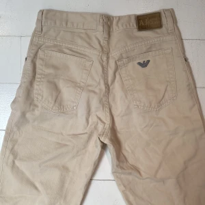 Beige raka Armani Jr jeans - Beige byxor från Armani Jeans med rak passform (ej skinny). Tillverkade i 100% bomull för en skön känsla och stilren look.