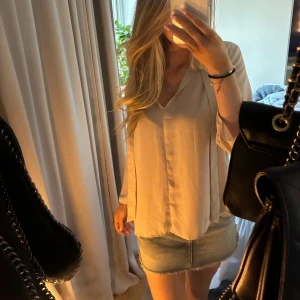 Beige blus med knytband - Säljer en stilren beige blus med långa ärmar och v-ringning. Blusen har tunna knytband framtill som ger en snygg detalj.  Materialet känns tunt och svalt, vilket gör den skön att bära under varmare dagar. Sällan använd, vet tyvärr ej vart jag köpt den!🌸💫🌟