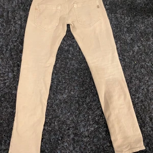 Beige jeans från Dondup  - Snygga beige jeans v från Dondup med klassisk femficksdesign och raka ben. Byxorna har diskreta röda detaljer vid fickan och ett ljust tyg som passar till det mesta. Perfekta för dig som gillar stilrena och enkla plagg.