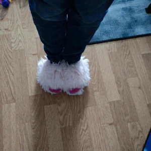 Fluffiga rosa tofflor med pälslook - Supermjuka och fluffiga tofflor i ljusrosa med inslag av starkare rosa framtill. Perfekta för att mysa runt hemma, med en riktigt skön och varm känsla tack vare det pälsliknande syntetmaterialet. Söt och lekfull design som sticker ut.