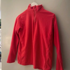 Röd fleece-tröja med half zip - Mysig röd fleece-tröja med hög krage och half zip-dragkedja. Perfekt för kyliga dagar och enkel att dra på över en t-shirt. Långärmad modell i mjukt fleecematerial som håller dig varm och bekväm. Ganska välanvänd men har inga defekter.