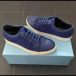 Blå sneakers från Lanvin i mocka och skinn - Snygga blå sneakers från Lanvin med ovandel i mocka och tåparti i skinn. Skorna har vita sulor och matchande blå snörning. Extremt fin och unik blå färg perfekt för sommaren!! Endast dust bag följer med!!! Uk 8 passar runt 42/43