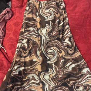 Brun mönstrad kjol - Säljer en midkjol med swirl-mönster i bruna, beige och vita toner. 