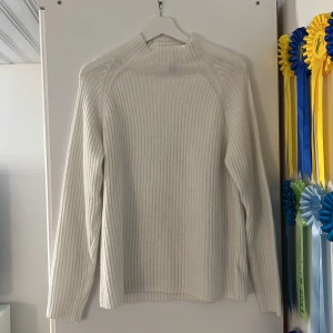 Vit ribbstickad tröja från New Yorker - Säljer en vit ribbstickad tröja från New Yorker i stl S med hög hals och lång ärm. Tröjan är i mjukt stickat material och har en clean, enkel look som är lätt att matcha med allt. Perfekt för dig som gillar stilrena vibes och vill ha något mysigt till kyligare dagar. Använd fåtal gånger